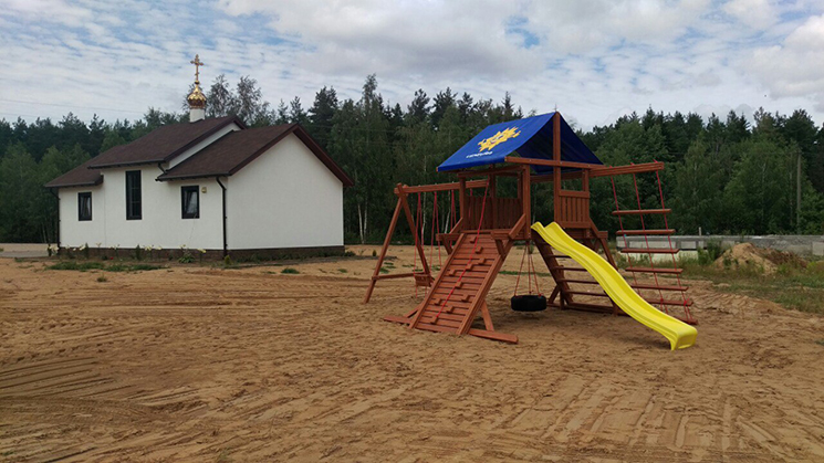 За храмом организована детская площадка с качелями, песочницей